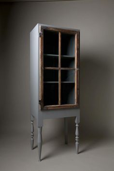 an old wooden cabinet with glass doors on the front and bottom shelves, against a gray background