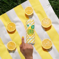 a person pointing at an orange juice can on a blanket with lemons around it