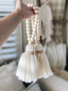 a person holding up a white beaded bell ornament with beads hanging from it