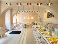 a long buffet with lots of food on the counter and lights hanging from the ceiling