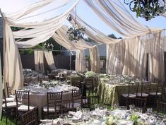 the tables are set up with white linens and draping for an outdoor wedding