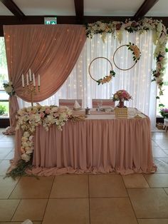 a table with flowers and candles on it in front of a curtained wall at a wedding reception