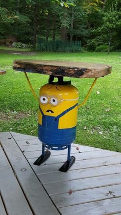 a yellow and blue cooler sitting on top of a wooden table next to a forest