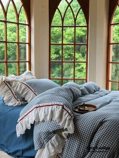 a bed with blue and white comforters in front of two large windowed windows