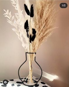 a vase filled with dry grass on top of a white and black tablecloth covered floor