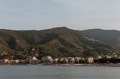 a body of water with buildings on the shore and mountains in the backgroud