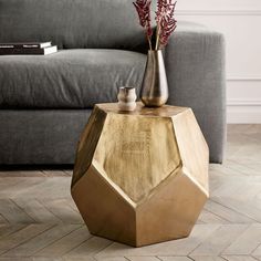 a table with two vases on top of it in front of a gray couch