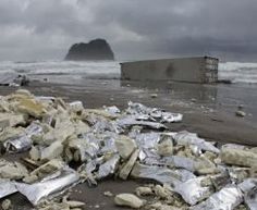 a pile of silver foil sitting on top of a sandy beach next to the ocean