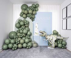 a room with balloons and an artificial dinosaur in the corner, next to a sign that says karmi