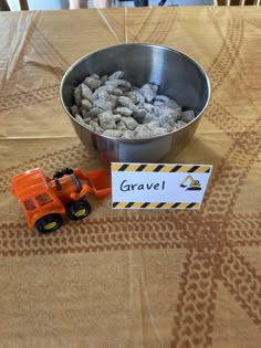 a metal bowl filled with gravel next to a sign on top of a wooden table