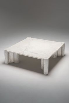 a white marble coffee table sitting on top of a gray floor with no one around it