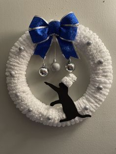 a white wreath with a black cat hanging from it