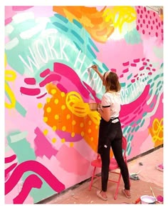 a woman is painting a large colorful wall