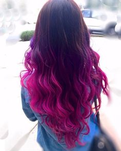 the back of a woman's head with long, wavy hair in pink and purple