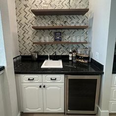 a kitchen with white cabinets and black counter tops