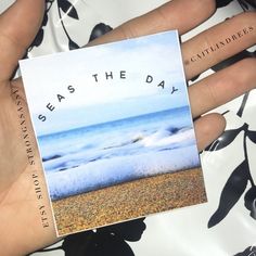 a person holding up a card with the words seas the day on it in their hand