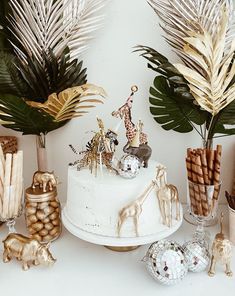 a white cake surrounded by palm leaves and other decorative items, including giraffes