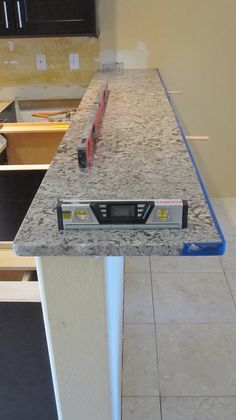 a kitchen counter top with an electronic device sitting on it's end in the middle