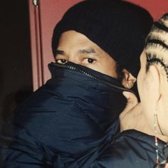 a man is covering his face with a black scarf and looking at another person's face