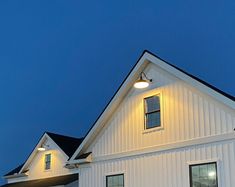 a white house is lit up at night with the moon in the sky behind it