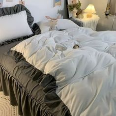 an unmade bed with white sheets and black ruffled bedspread