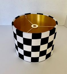 a black and white checkered lamp shade with a gold clock on the front side