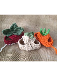 three crocheted baby booties sitting on top of a bed next to each other