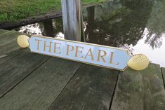 there is a sign that says the pearl on top of a wooden deck next to water