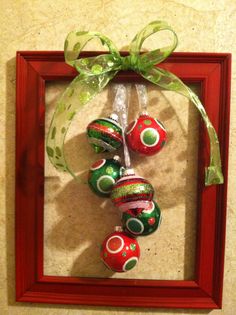 an ornament hanging in a red frame with green ribbon and bow on it