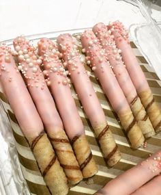 there are many pink and white candles in the trays with beads on them that look like they were made out of marshmallows