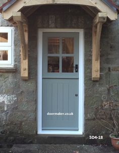 the front door is made of wood and has two windows on each side, along with a small potted plant next to it