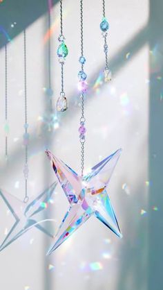 an origami star hanging from a chain in the sun with crystal balls and chains attached to it