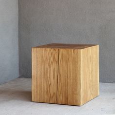 a wooden block sitting on top of a cement floor next to a gray concrete wall