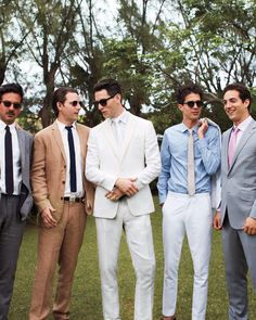 a group of men standing next to each other wearing suits and ties on the grass