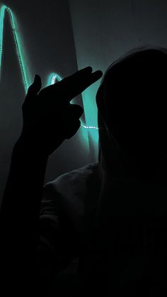 a person in a dark room holding a cell phone up to their face and pointing at the screen