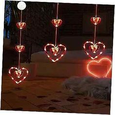 three heart shaped lights hanging from strings in the air over a patio area with a dog laying on the floor