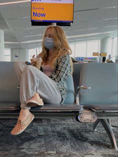 a woman wearing a face mask sitting on an airport bench