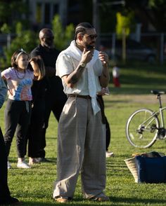 a man standing on top of a lush green field holding a cell phone to his ear