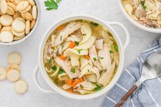 two bowls filled with chicken noodle soup next to crackers