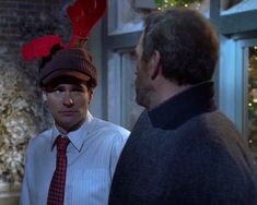 a man wearing a reindeer hat with antlers on his head and another man standing next to him