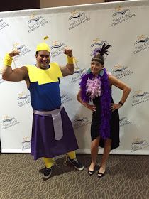 two people in costumes standing next to a wall with a sign on it that says,