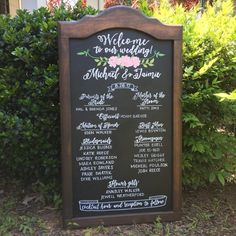 a chalkboard sign in front of bushes with flowers on it that says welcome to our wedding