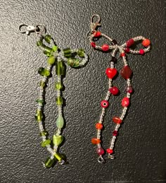 two necklaces made out of glass beads on a black surface, one is red and the other is green