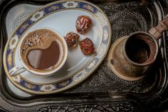 there is a cup of coffee and some candies on the tray