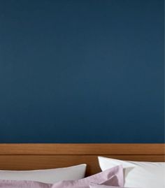 a bed with white pillows and blue walls in the background, along with a wooden headboard