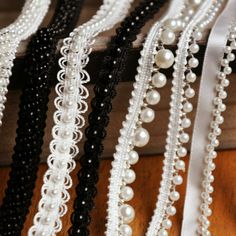 several different types of pearls and beads on display in a store window sill with ribbons hanging from them