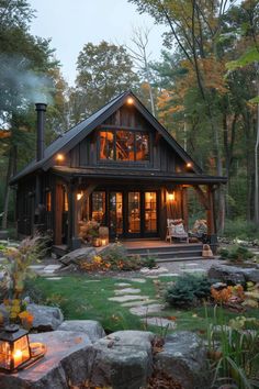 a small cabin in the woods surrounded by rocks and trees with lit candles on it