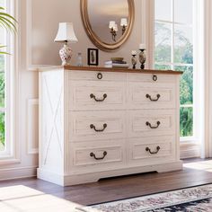 a white dresser sitting next to a window with a mirror on top of it in a room