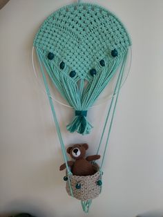 a crocheted stuffed bear in a hot air balloon hanging on the wall next to a teddy bear