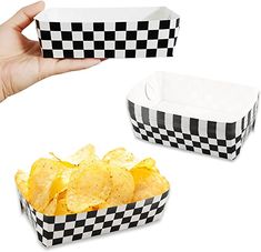 hand holding up two black and white checkered paper containers filled with potato chips on top